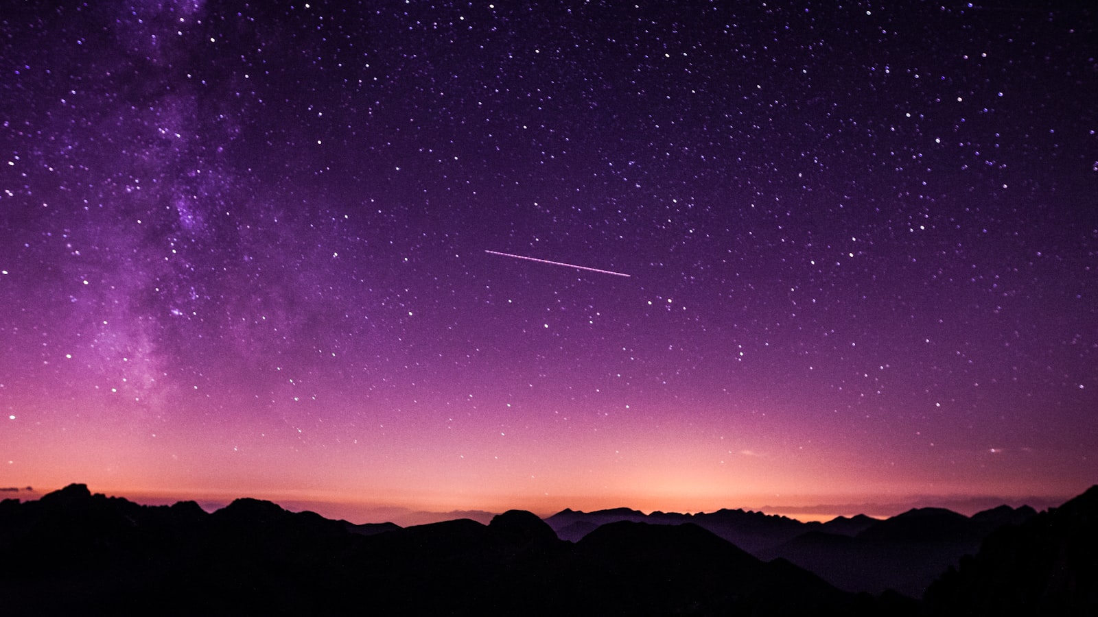 The Milky Way arching across a dark night sky over the horizon